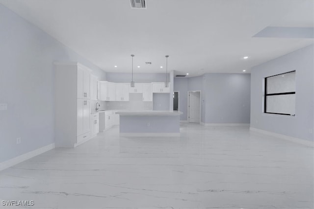 kitchen featuring white cabinetry, a center island, hanging light fixtures, and sink