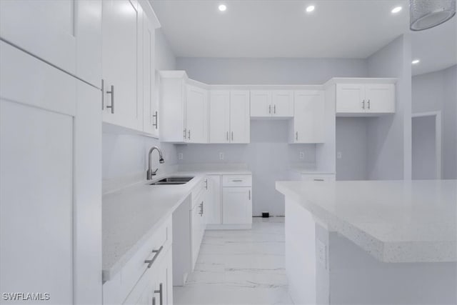 kitchen featuring light stone counters, sink, and white cabinets