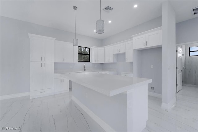 kitchen with sink, a center island, pendant lighting, and white cabinets