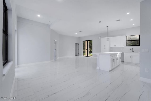 kitchen with white cabinets, sink, pendant lighting, and a kitchen island