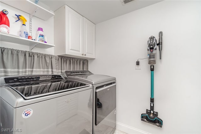 laundry room with separate washer and dryer and cabinets