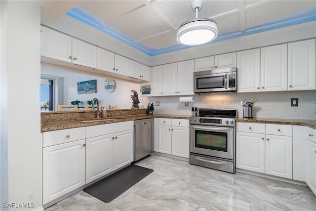 kitchen with stainless steel appliances, backsplash, sink, white cabinets, and dark stone countertops