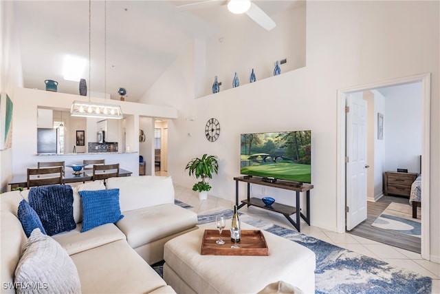 living room with ceiling fan, high vaulted ceiling, and light tile patterned floors