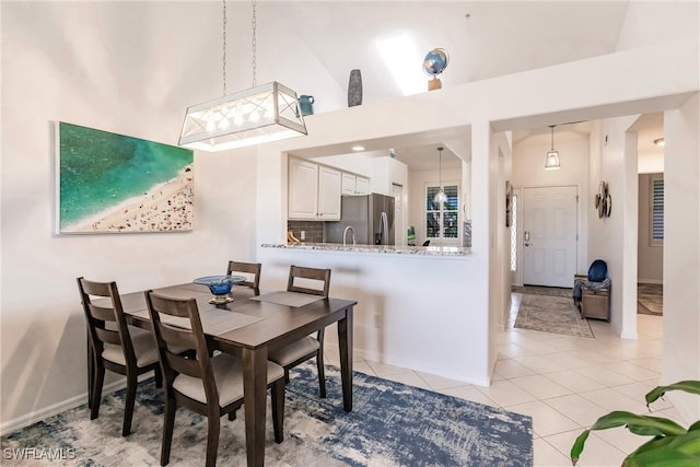 dining room with light tile patterned flooring and high vaulted ceiling