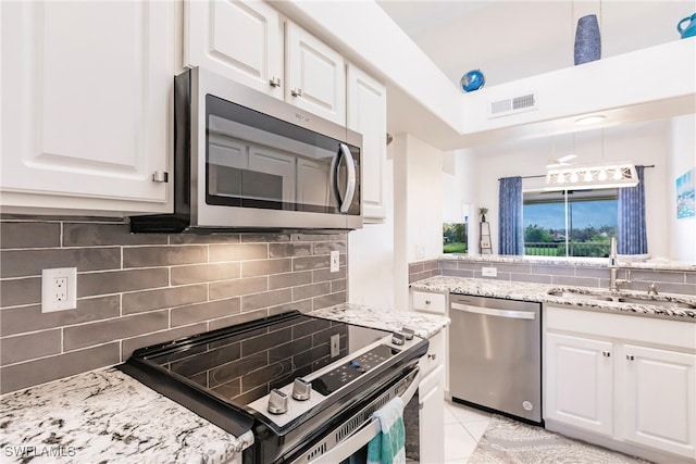 kitchen featuring white cabinets, tasteful backsplash, appliances with stainless steel finishes, sink, and decorative light fixtures