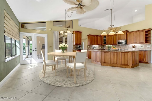 dining room with high vaulted ceiling, french doors, light tile patterned floors, and ceiling fan with notable chandelier