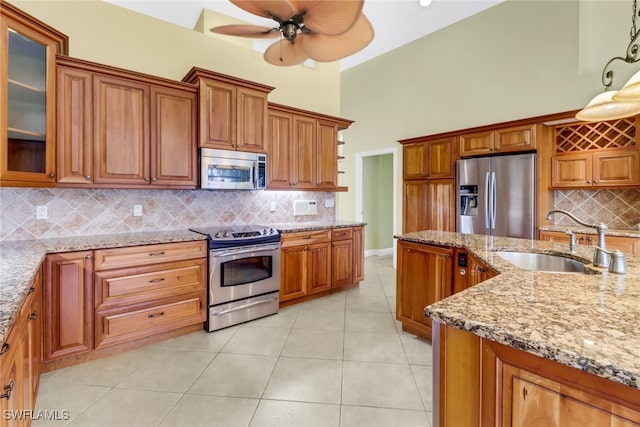 kitchen featuring decorative backsplash, sink, light stone counters, and stainless steel appliances