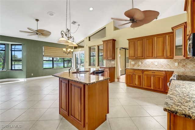 kitchen featuring ceiling fan with notable chandelier, stainless steel appliances, a center island with sink, high vaulted ceiling, and decorative light fixtures