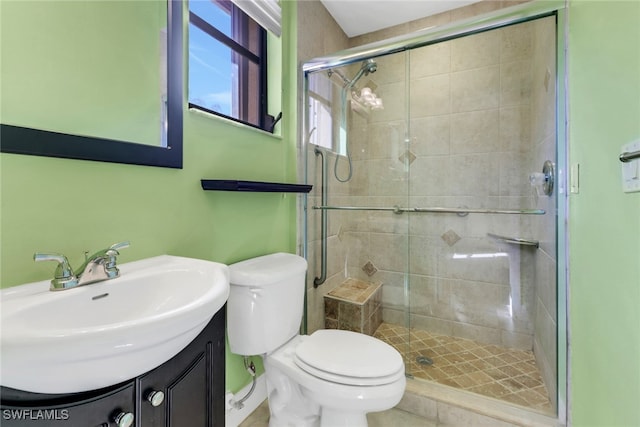 bathroom featuring a shower with door, vanity, and toilet