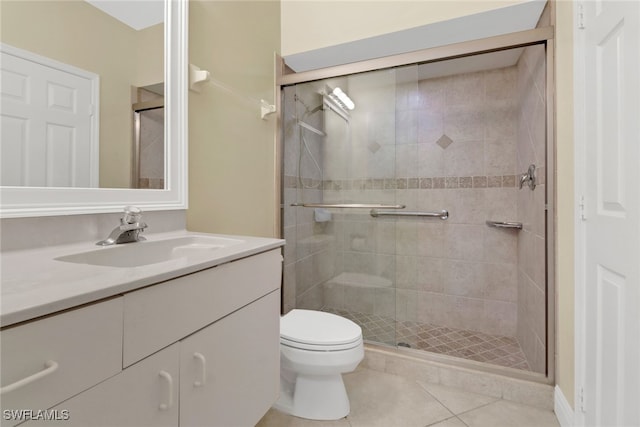 bathroom with vanity, tile patterned floors, toilet, and a shower with door