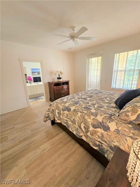 bedroom with ensuite bathroom, a ceiling fan, and light wood-style flooring