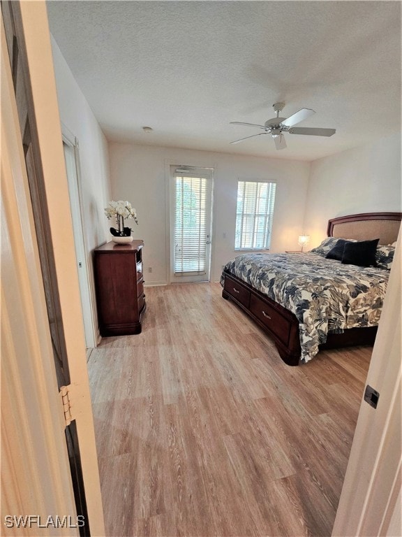 bedroom with light hardwood / wood-style flooring, a textured ceiling, and ceiling fan