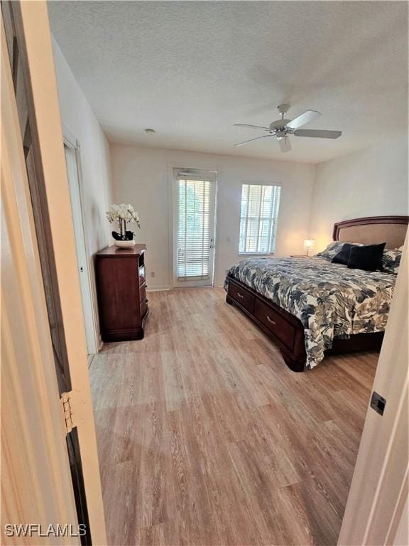 bedroom featuring a textured ceiling, ceiling fan, and light wood-style flooring