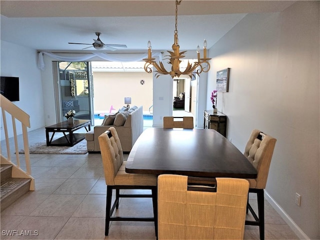 dining area featuring light tile patterned floors, ceiling fan with notable chandelier, and stairs