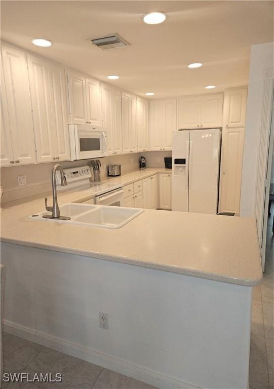 kitchen featuring visible vents, light countertops, a peninsula, white appliances, and white cabinetry