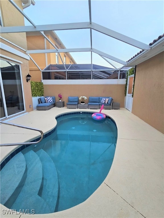 view of pool with a patio, an outdoor living space, and glass enclosure