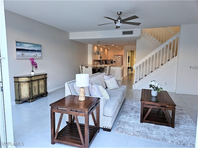 living area featuring visible vents, stairway, baseboards, ceiling fan with notable chandelier, and light tile patterned flooring