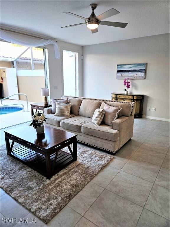 living room with baseboards, a ceiling fan, and light tile patterned flooring