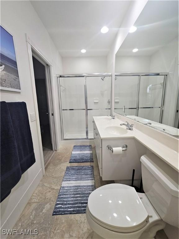 bathroom featuring stone finish floor, a shower stall, vanity, toilet, and recessed lighting