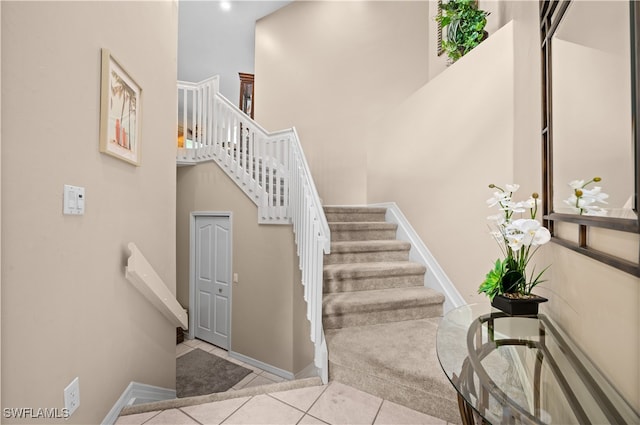 staircase with tile patterned flooring and a high ceiling