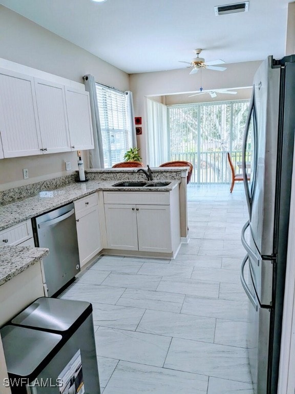 kitchen with ceiling fan, kitchen peninsula, sink, appliances with stainless steel finishes, and white cabinets