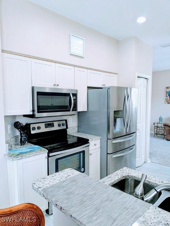 kitchen featuring light stone countertops, white cabinets, and appliances with stainless steel finishes