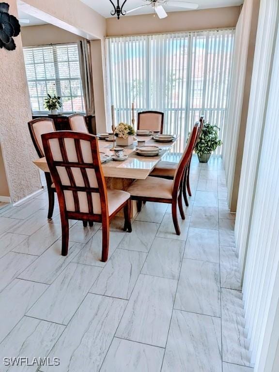 dining space featuring ceiling fan with notable chandelier