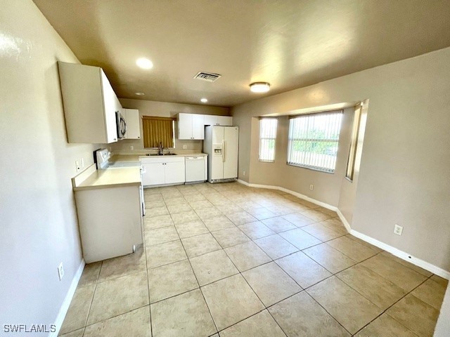 kitchen with sink, white cabinetry, white appliances, and light tile patterned floors