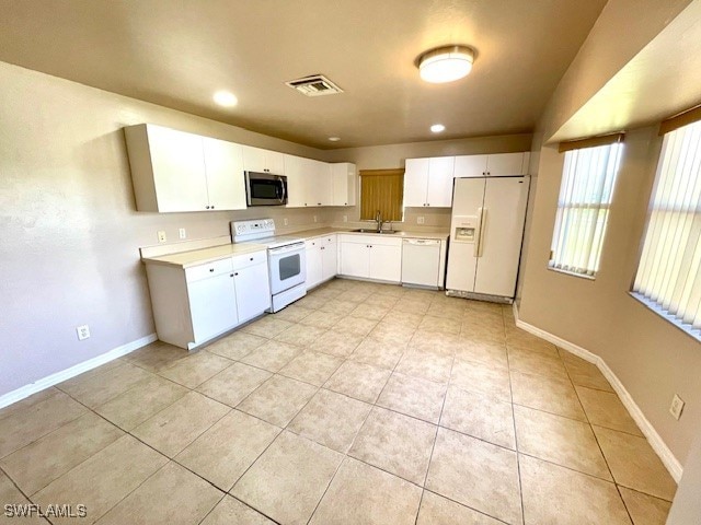 kitchen with white cabinetry, sink, light tile patterned floors, and white appliances