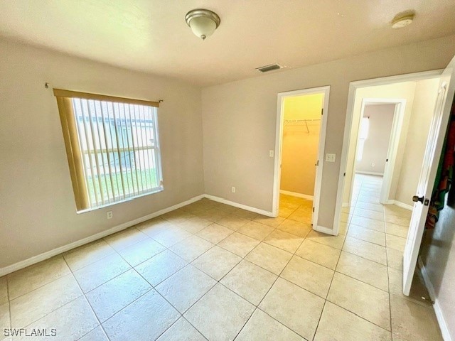 unfurnished bedroom with a walk in closet, a closet, and light tile patterned floors