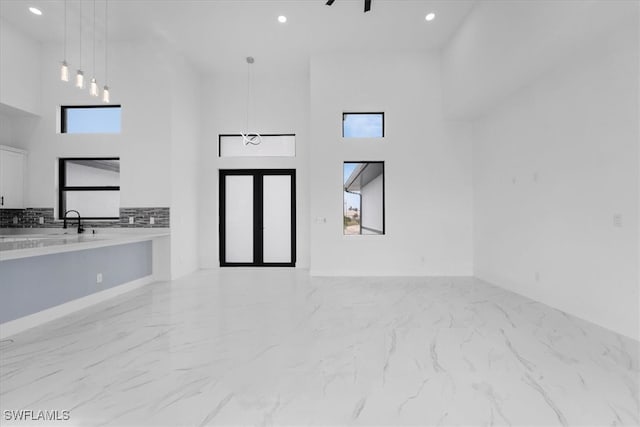 unfurnished living room with a towering ceiling and sink