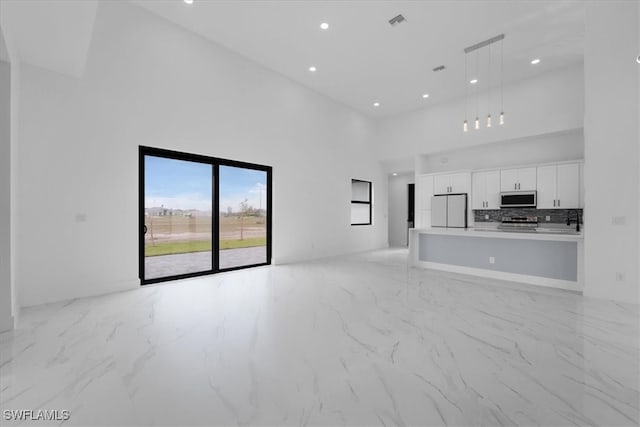 unfurnished living room featuring a towering ceiling