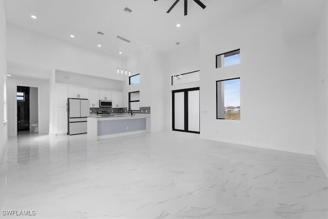 unfurnished living room with sink, a high ceiling, and ceiling fan