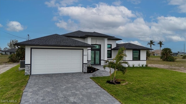 prairie-style home with cooling unit, a front lawn, and a garage