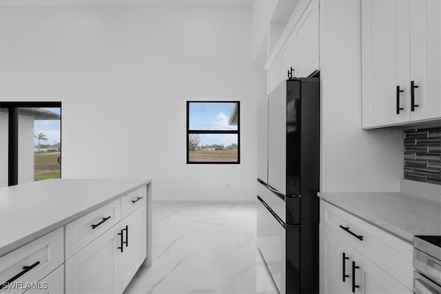 kitchen featuring decorative backsplash, white cabinetry, and black fridge