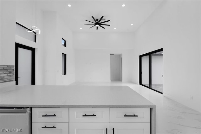 interior space featuring white cabinetry, a towering ceiling, and ceiling fan