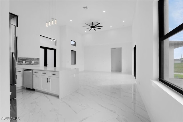 kitchen featuring a high ceiling, decorative light fixtures, white cabinetry, appliances with stainless steel finishes, and ceiling fan