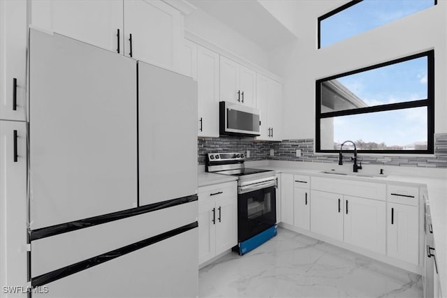 kitchen featuring tasteful backsplash, range with electric stovetop, white cabinetry, sink, and white refrigerator