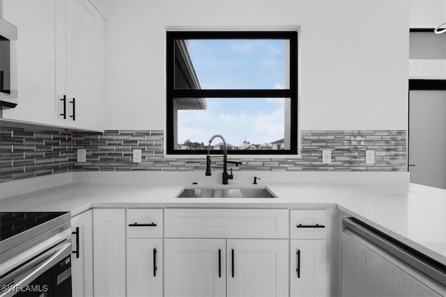 kitchen with appliances with stainless steel finishes, white cabinetry, tasteful backsplash, and sink