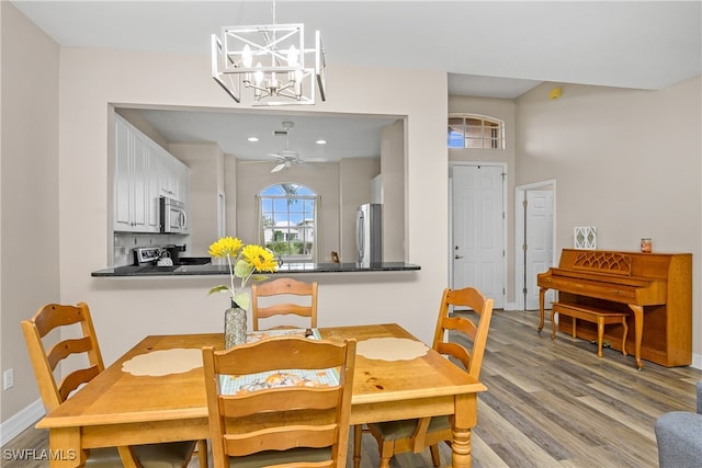 dining area featuring ceiling fan with notable chandelier and light hardwood / wood-style flooring