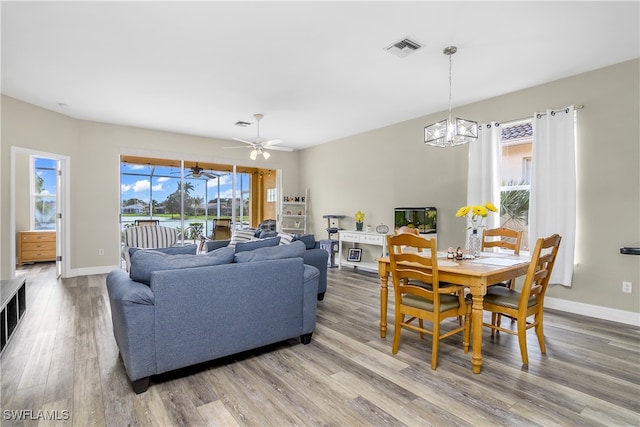 living room featuring ceiling fan with notable chandelier and hardwood / wood-style flooring