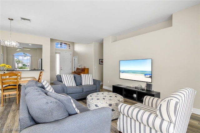 living room with hardwood / wood-style floors and ceiling fan with notable chandelier