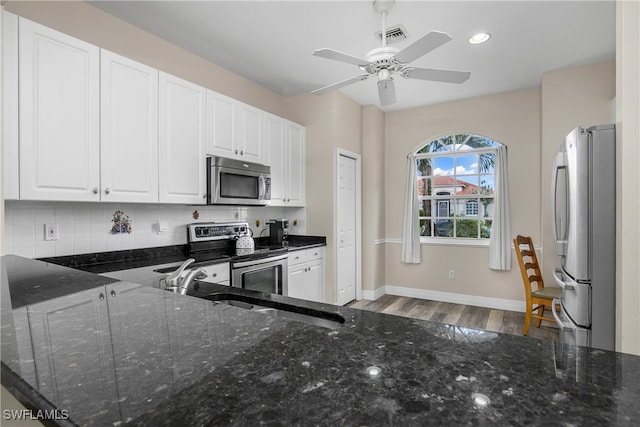 kitchen with dark stone counters, white cabinets, ceiling fan, and stainless steel appliances