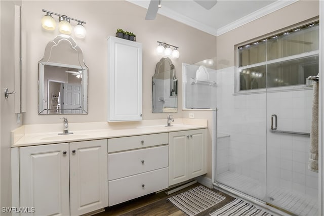 bathroom with wood-type flooring, ornamental molding, vanity, ceiling fan, and a shower with shower door