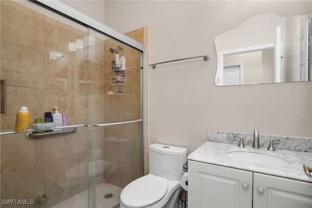 bathroom featuring an enclosed shower, vanity, and toilet