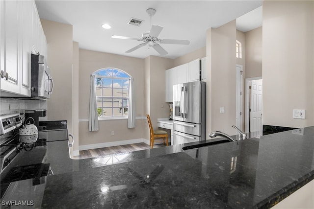 kitchen with white cabinetry, kitchen peninsula, stainless steel appliances, and hardwood / wood-style flooring