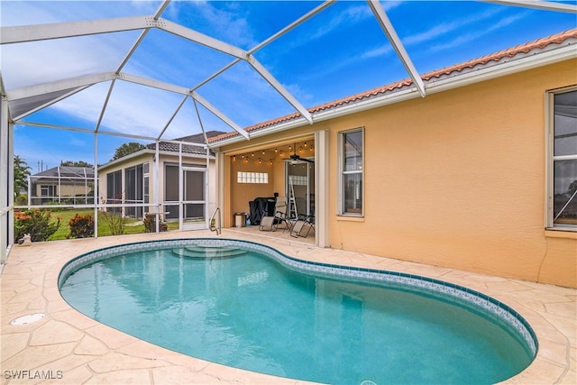 view of swimming pool featuring ceiling fan, a lanai, and a patio area