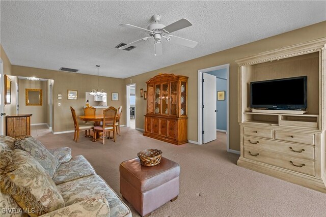 living room featuring visible vents, baseboards, light colored carpet, and ceiling fan with notable chandelier