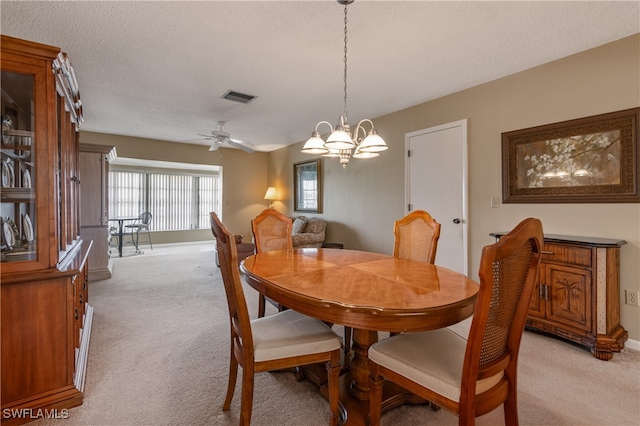 dining space featuring light carpet, a textured ceiling, and ceiling fan with notable chandelier