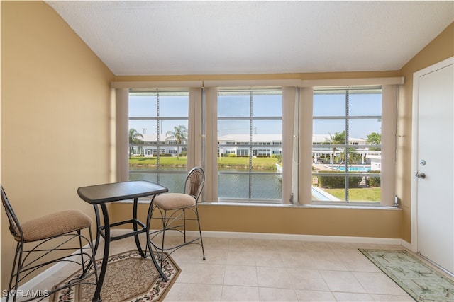 sunroom with a water view, a healthy amount of sunlight, and vaulted ceiling